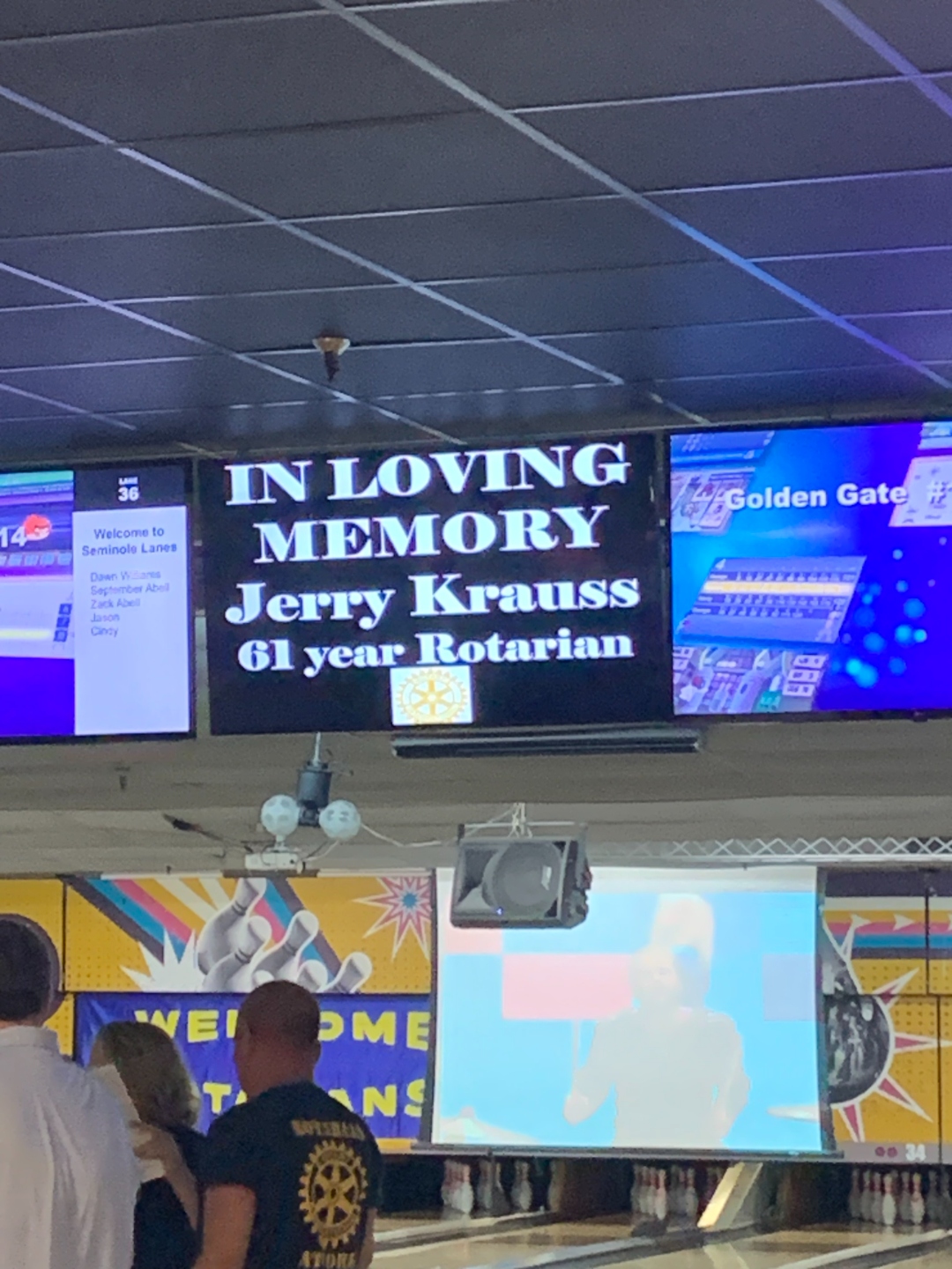 A tribute displayed on the lane-side monitors at Seminole Lanes reading 'In Loving Memory — Jerry Krauss — 61 year Rotarian.'